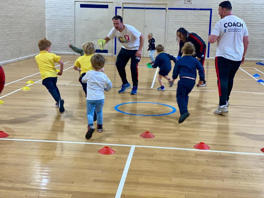 Kids playing with their coach inside the gymnasium